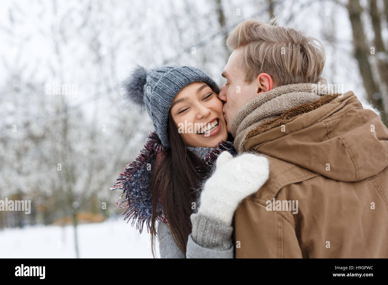 Guy kissing his girlfriend on cheek in embrace Stock Photo