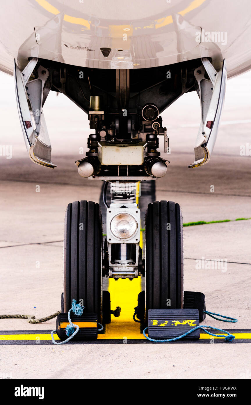 Nose wheel of a Boeing 737 with chocks to prevent movement. Stock Photo