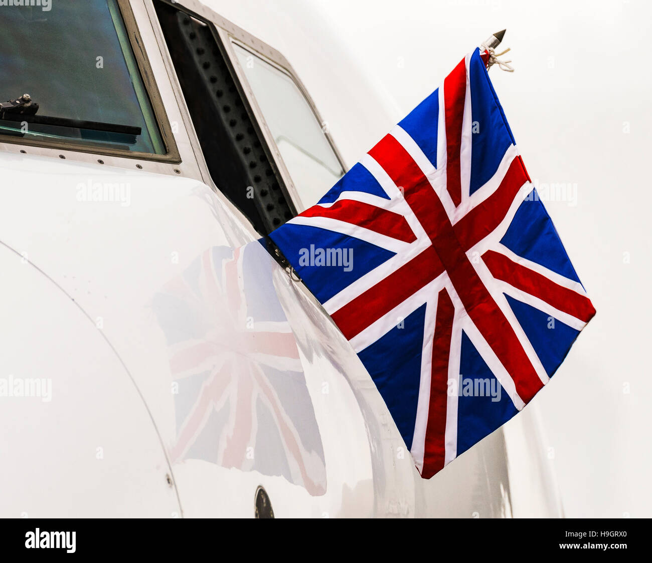 Pilot of a 737 on a diplomatic flight flies a Union Flag from the cockpit window. Stock Photo