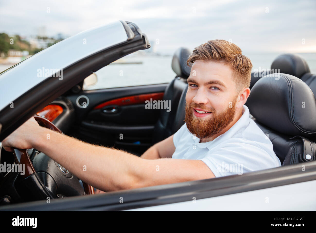 Portrait of young handsome smiling man sitting in his own car Stock ...