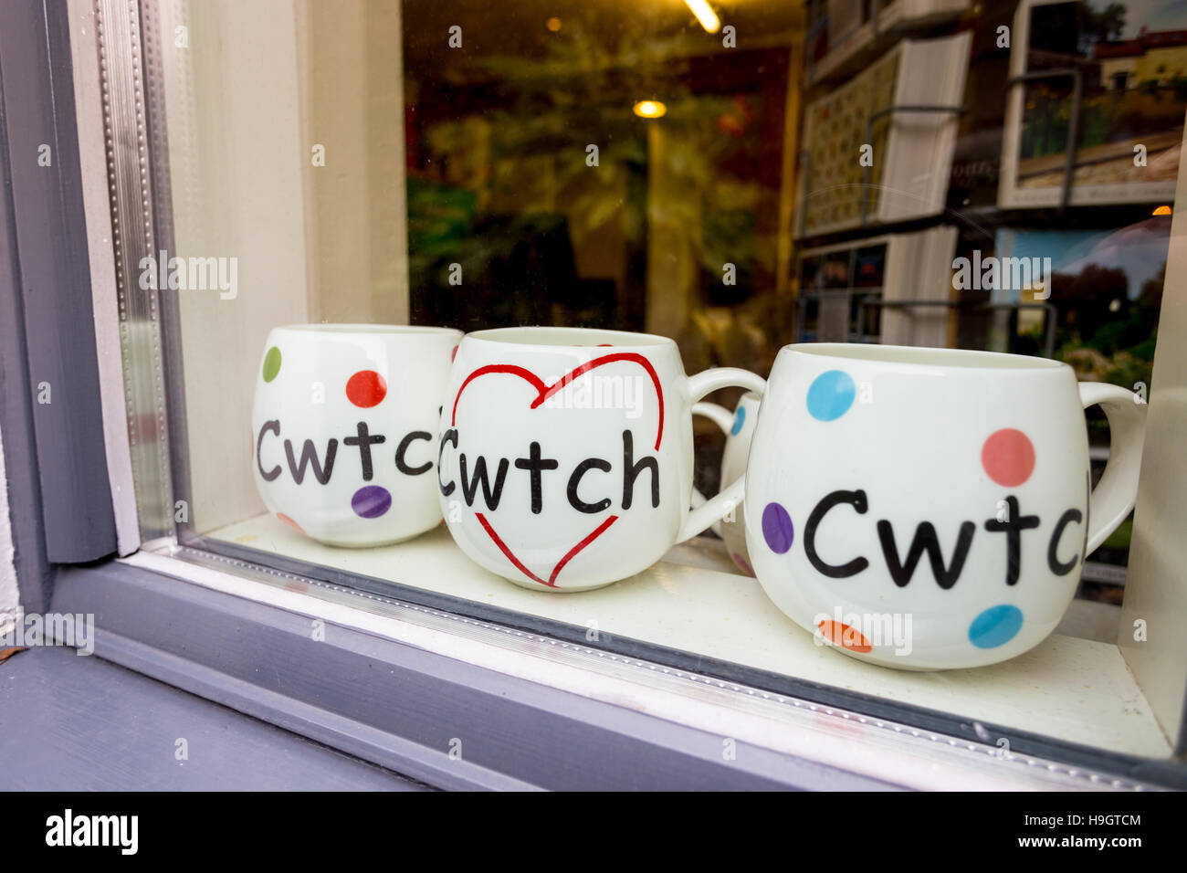 Three mugs with the Welsh language word Cwtch, meaning cuddle or hug in a shop window. Stock Photo