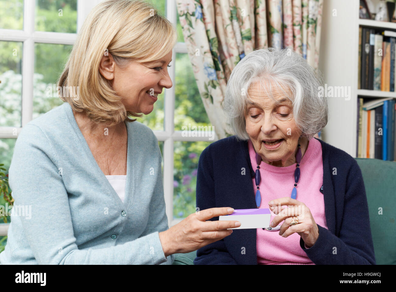 Female Neighbor Helping Senior Woman With Medication Stock Photo