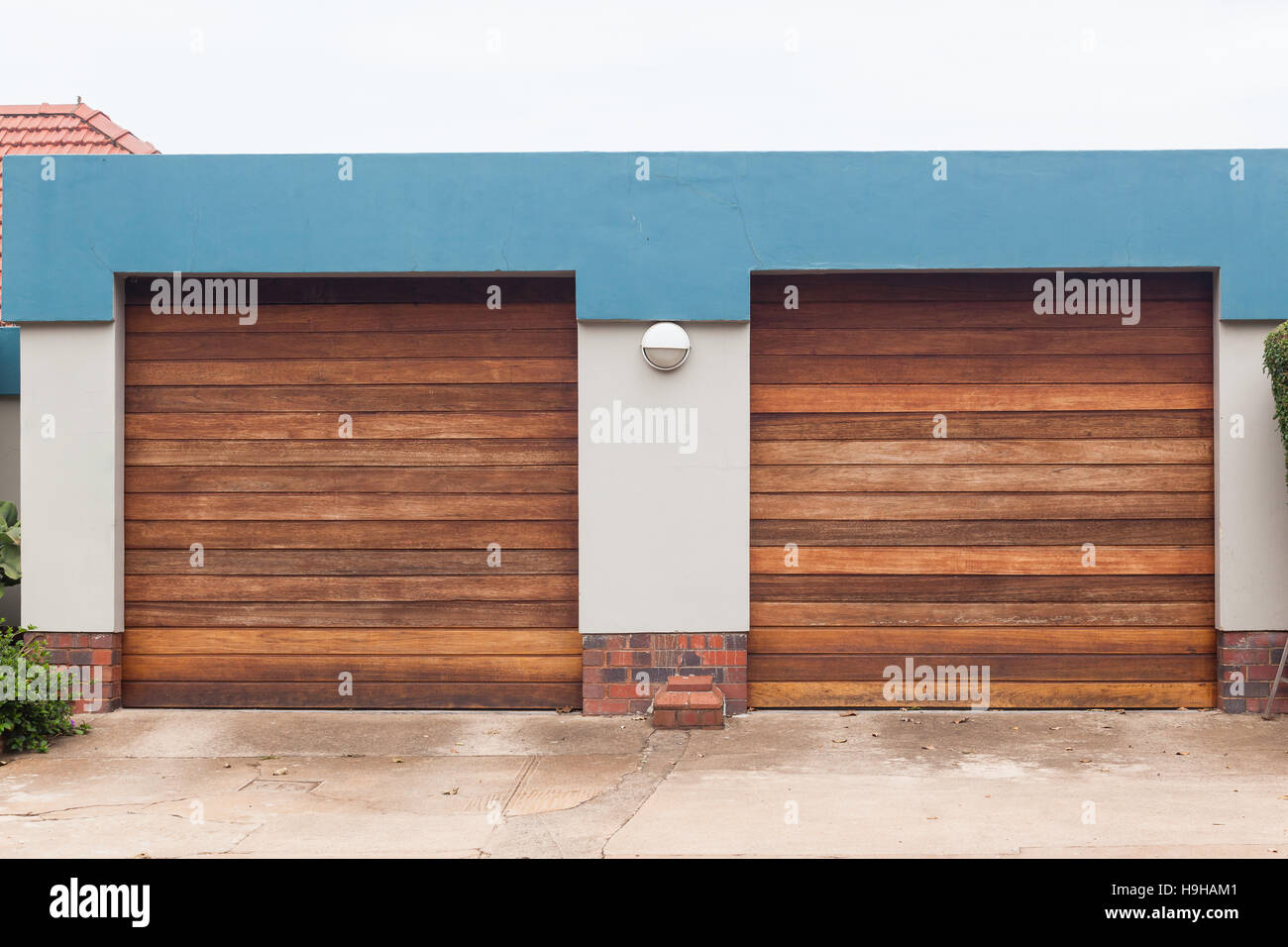 Garage two roll up wood doors for vehicles on roadside entrance. Stock Photo