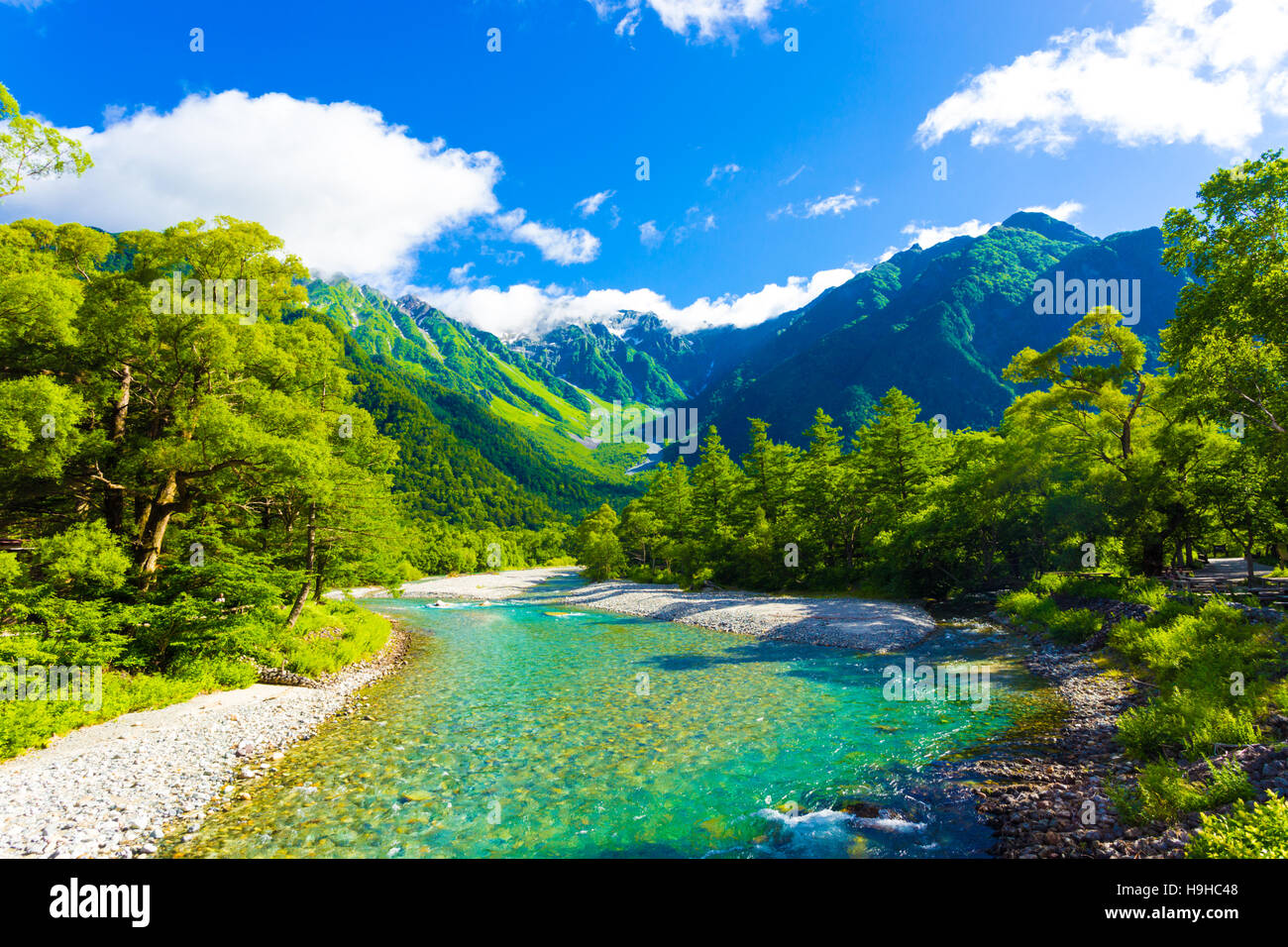 The pristine alpine water of Azusa River flowing in front of landscape view of Mount Hotaka-Dake on a sunny day in Kamikochi Stock Photo