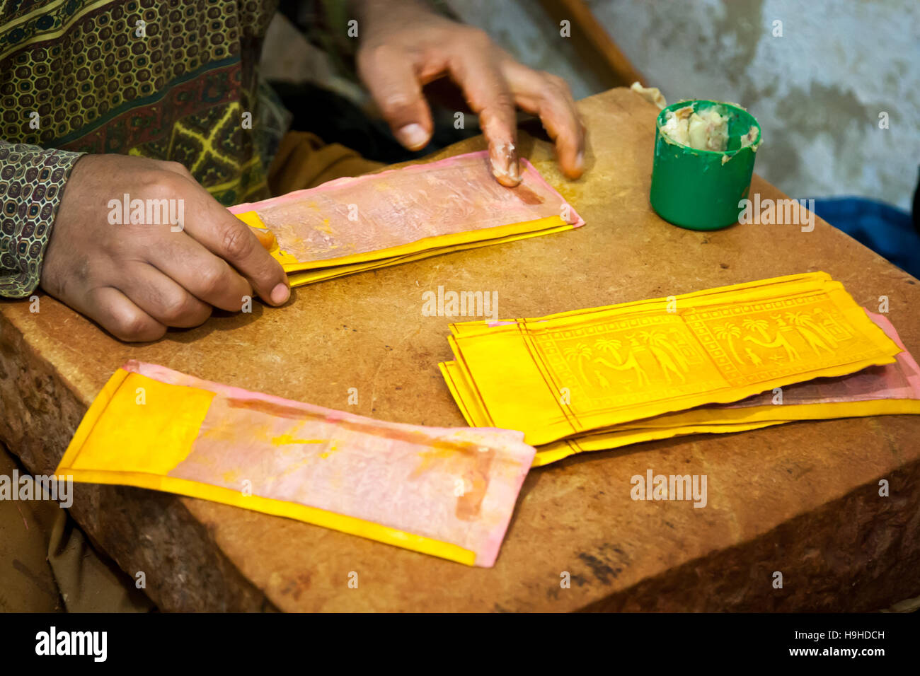 A craftsman glues yellow leather pieces embossed with palm and camel motifs to make wallets in Fès, Morocco. The leather artisans of Fès are particularly proud of the exclusive use of natural colors to dye goat or camel skins Stock Photo
