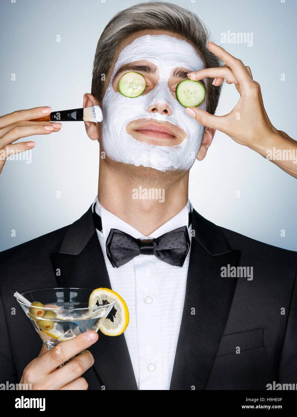 Gentleman receiving spa facial treatment. Photo of Handsome man with a facial mask on his face and cucumber on his eyes. Grooming himself Stock Photo