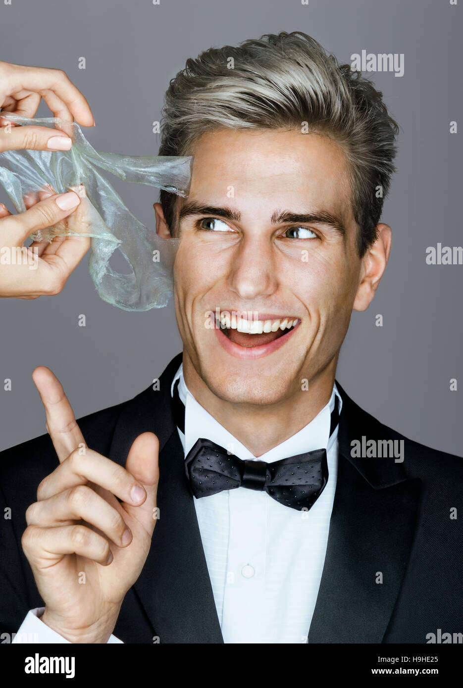 Smiling man in black suit removes peeling off a facial mask. Photo happy  rich man on gray background. Skin care concept Stock Photo - Alamy