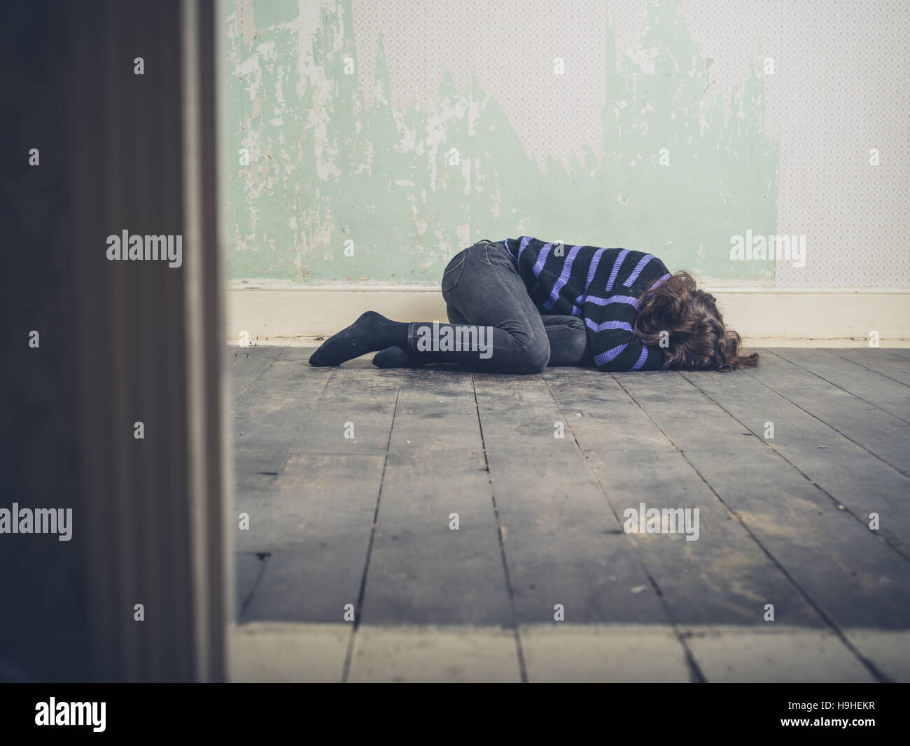 A sad young woman is lying on the floor in an empty room Stock Photo ...