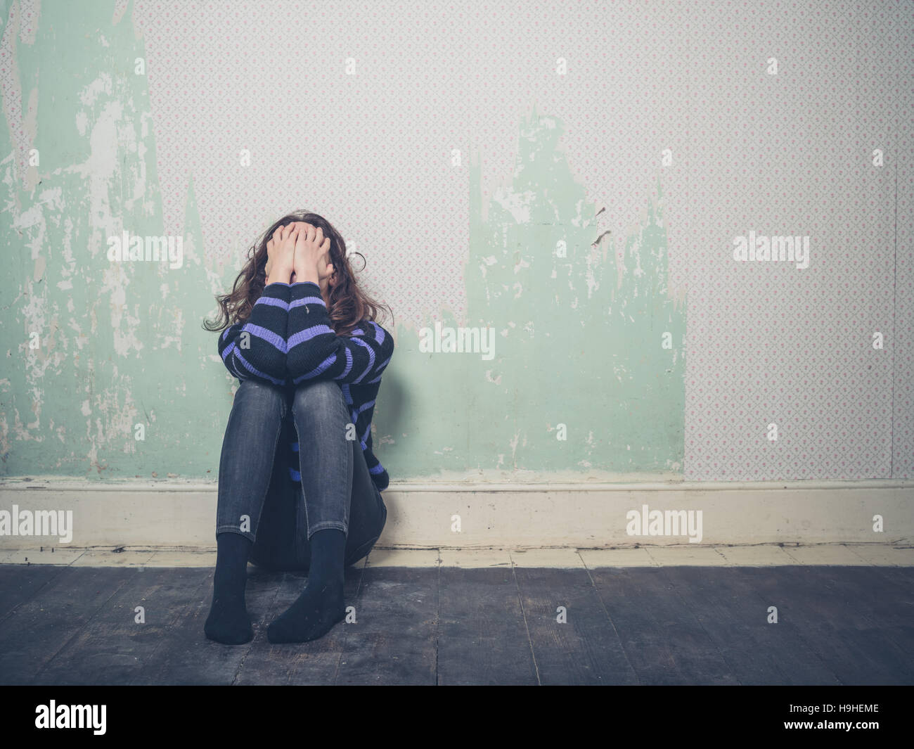 A sad young woman is sitting on the floor in an empty room Stock Photo ...