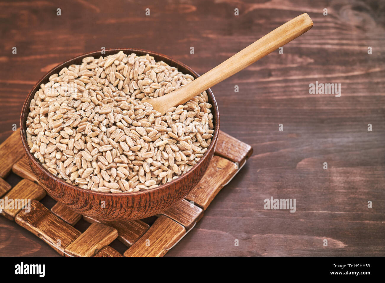 Spelt grain (dinkel wheat) in wooden bowl. Copy space Stock Photo