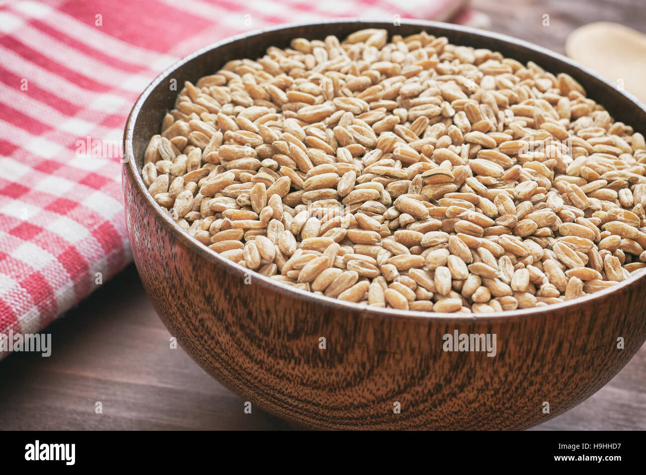 Spelt grain (dinkel wheat) in wooden bowl Stock Photo