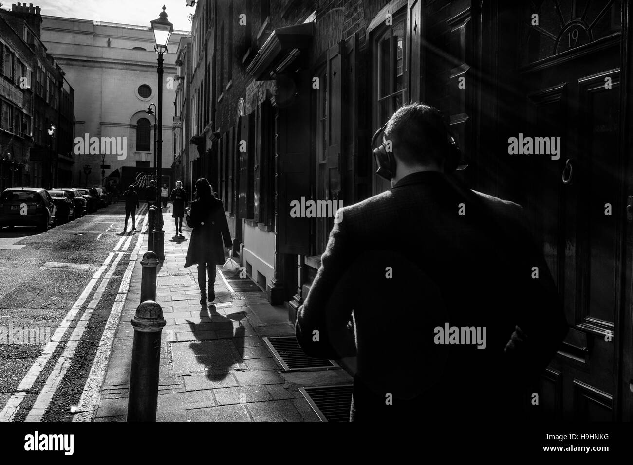 London black and white street photography: Man wearing headphones walking in street, Shoreditch, London Stock Photo
