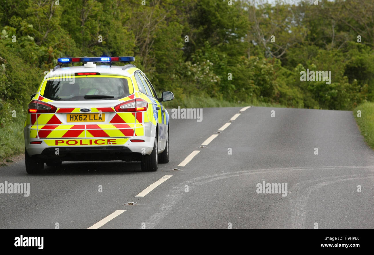 A Hampshire Constabulary police car responds on a rural country road on blue lights Stock Photo