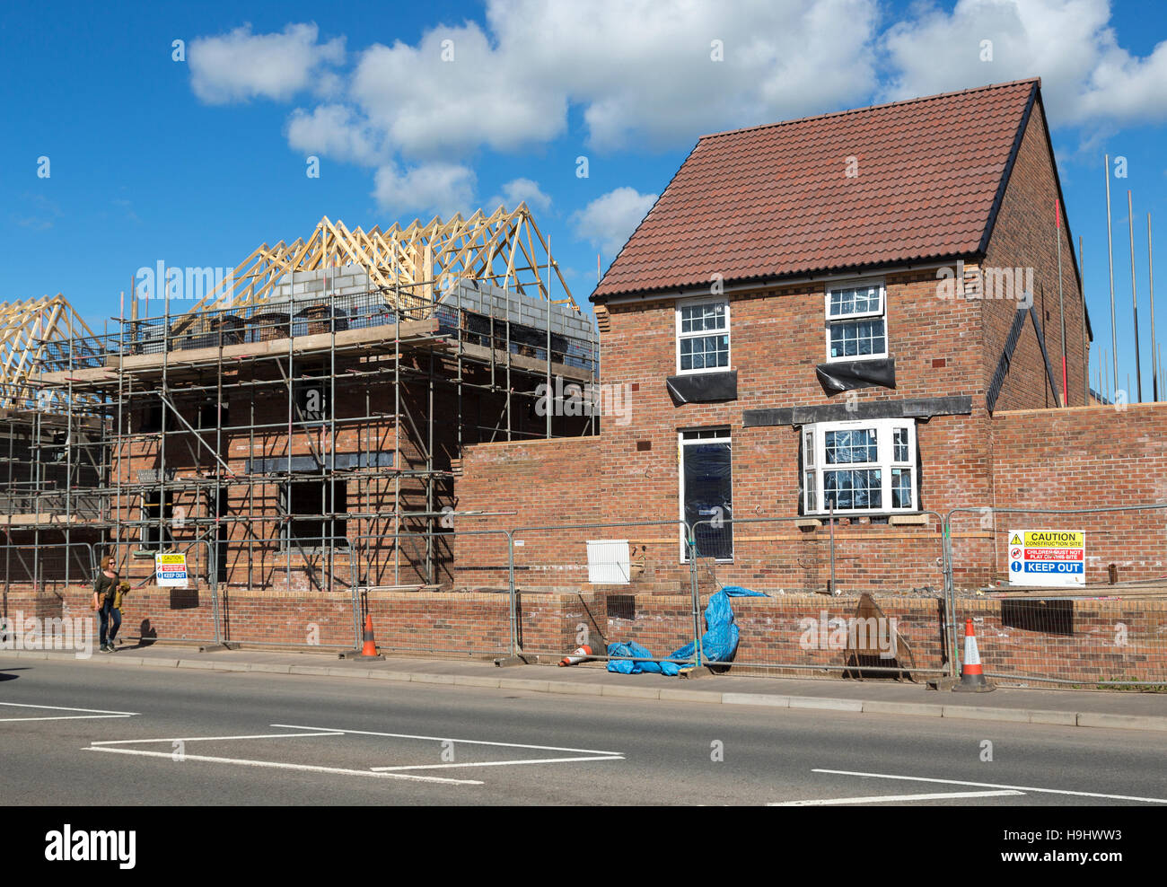 Person walking past new house building on a new estate on the outskirts