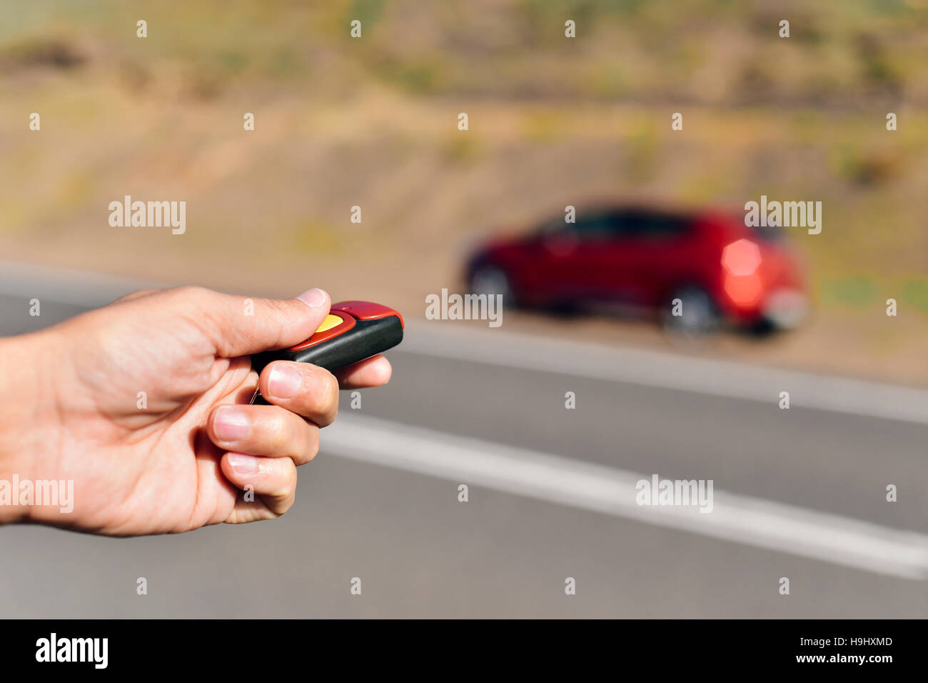 closeup of a young caucasian man opening or closing his car with the control remote key parked next to the road Stock Photo