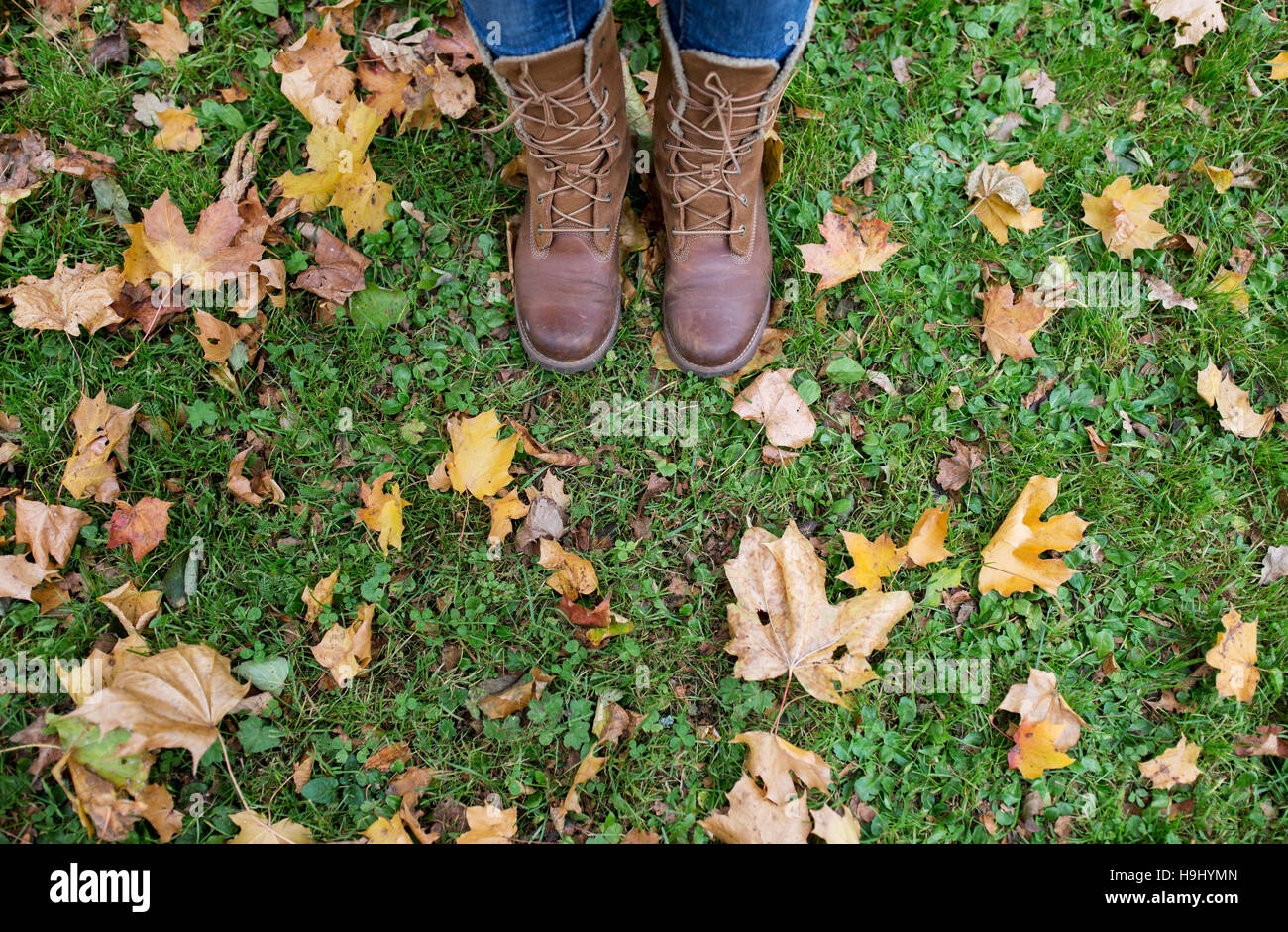 female feet in boots and autumn leaves on grass Stock Photo Alamy