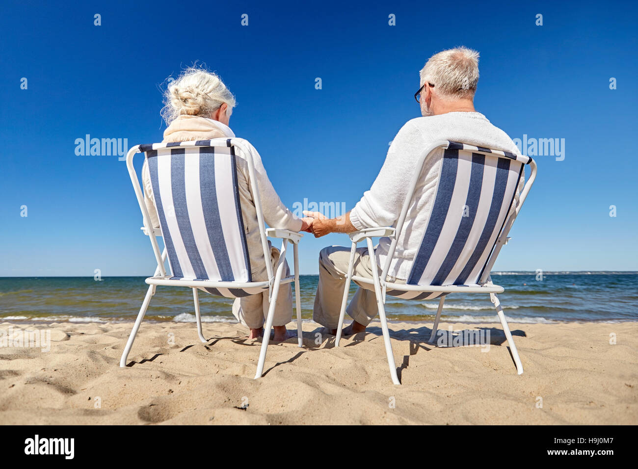 senior couple sitting on chairs at summer beach Stock Photo - Alamy