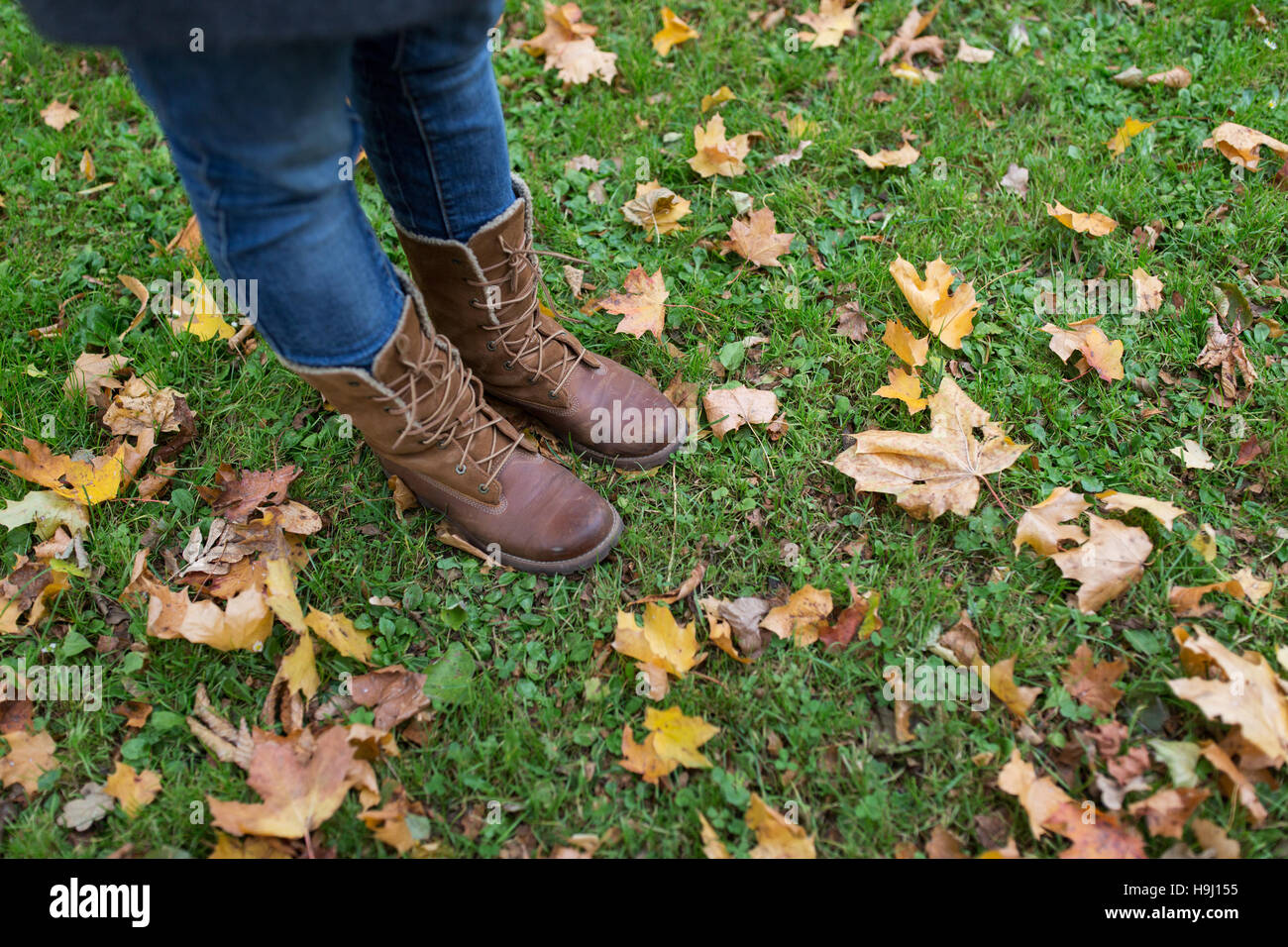 female feet in boots and autumn leaves on grass Stock Photo Alamy