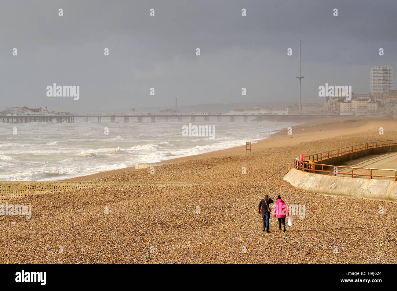 Brighton 22 Nov 2016: Two people brave Brighton Beach just after Storm Angus has passed through, Stock Photo
