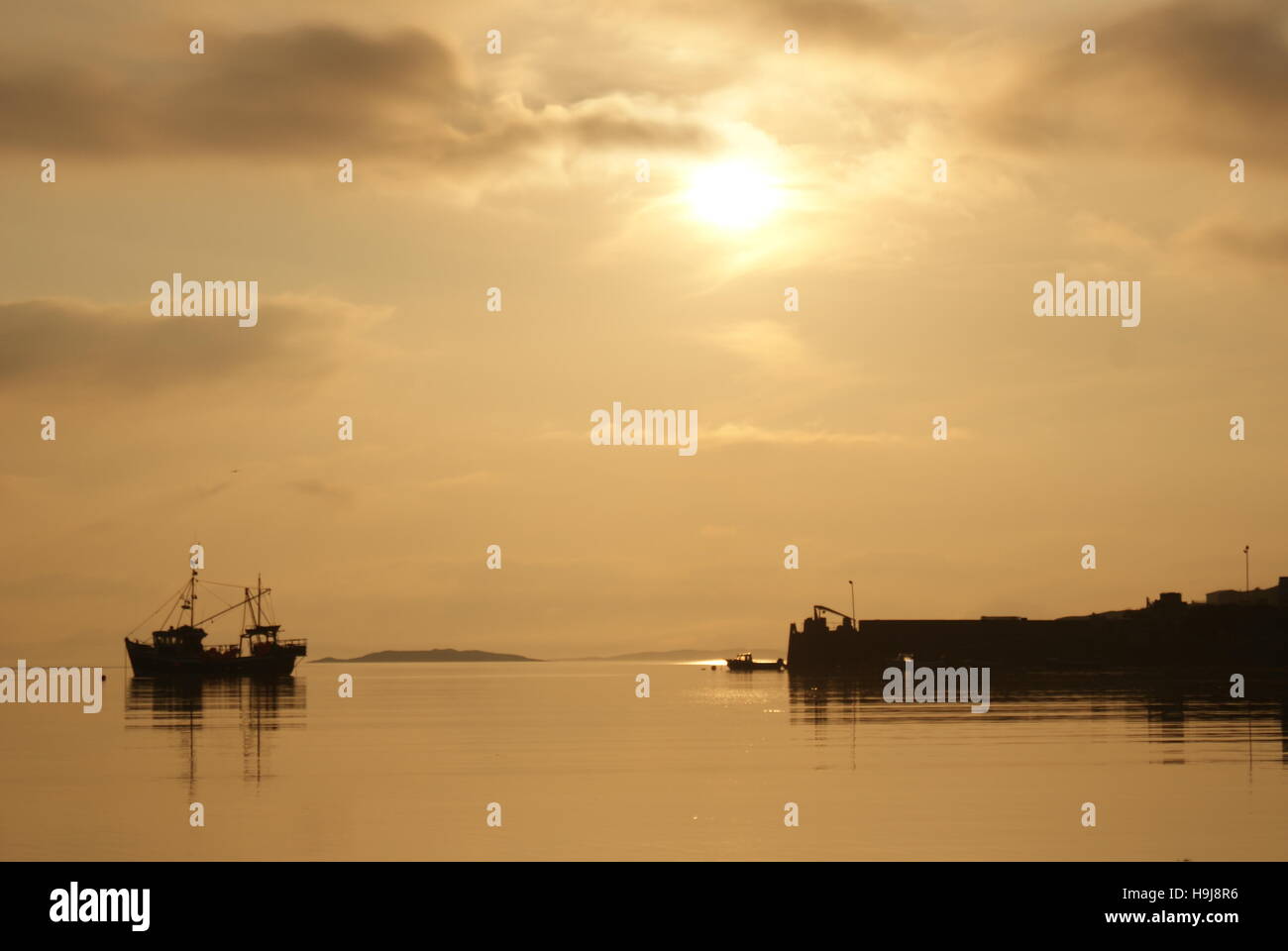 A boat and Pier silhouetted against a golden sky Stock Photo - Alamy