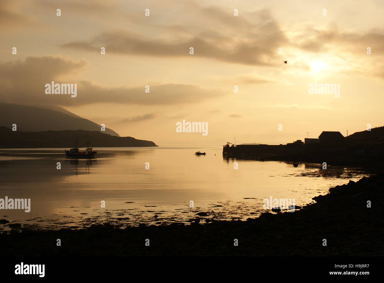 A boat and Pier silhouetted against a golden sky Stock Photo - Alamy