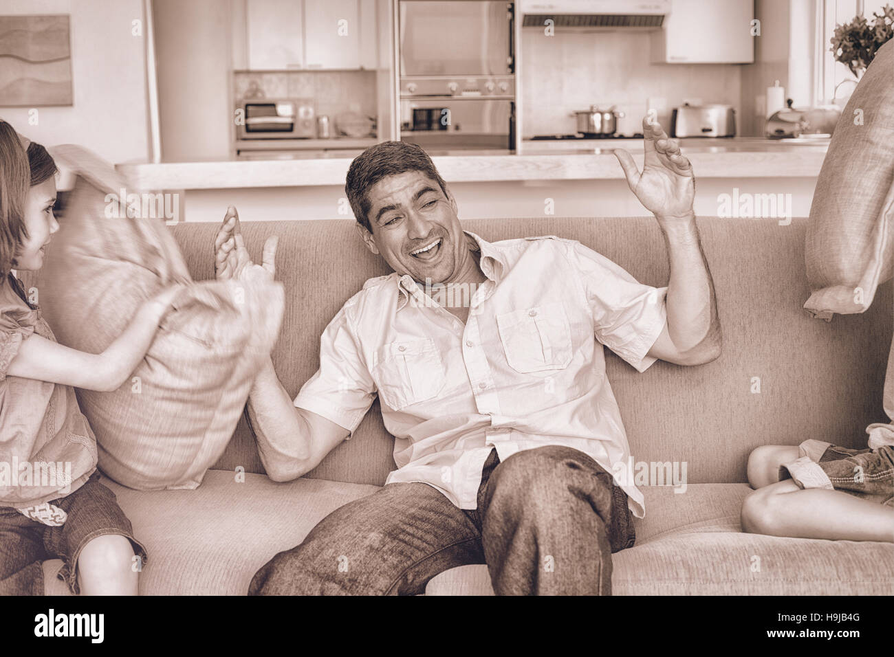 Family having pillow fight on sofa Stock Photo