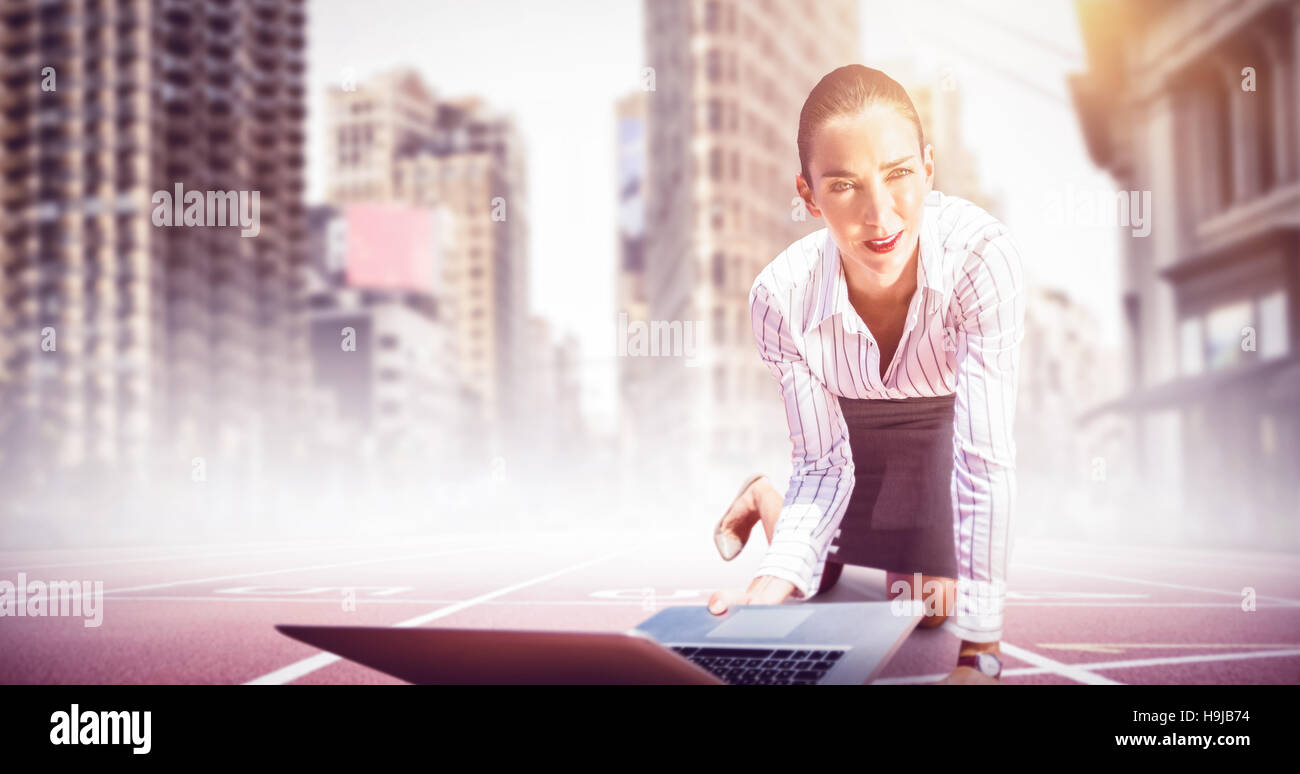 Composite image of businesswoman on knees holding a laptop Stock Photo