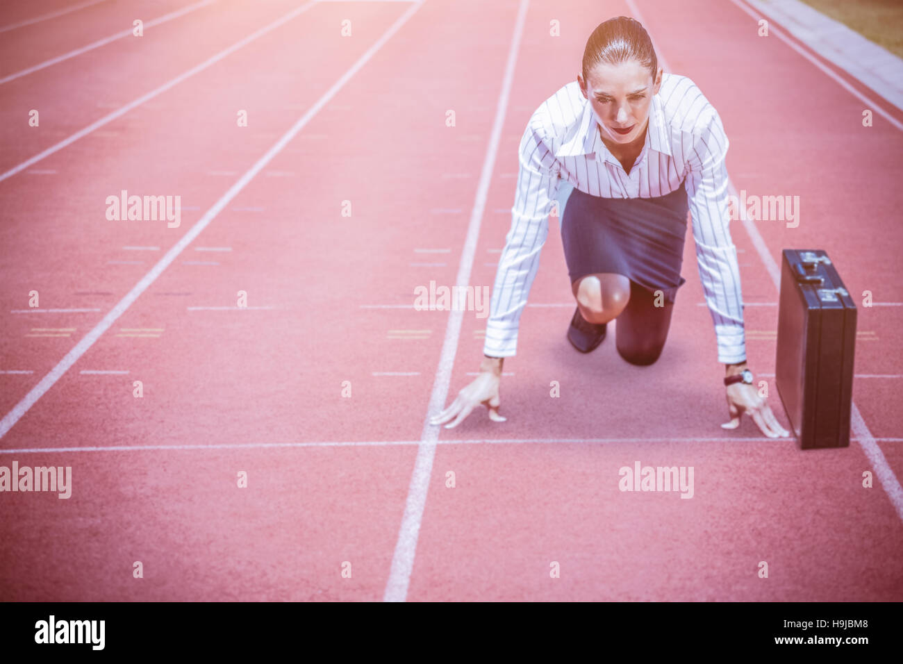Composite image of concentrate woman in starting blocks Stock Photo