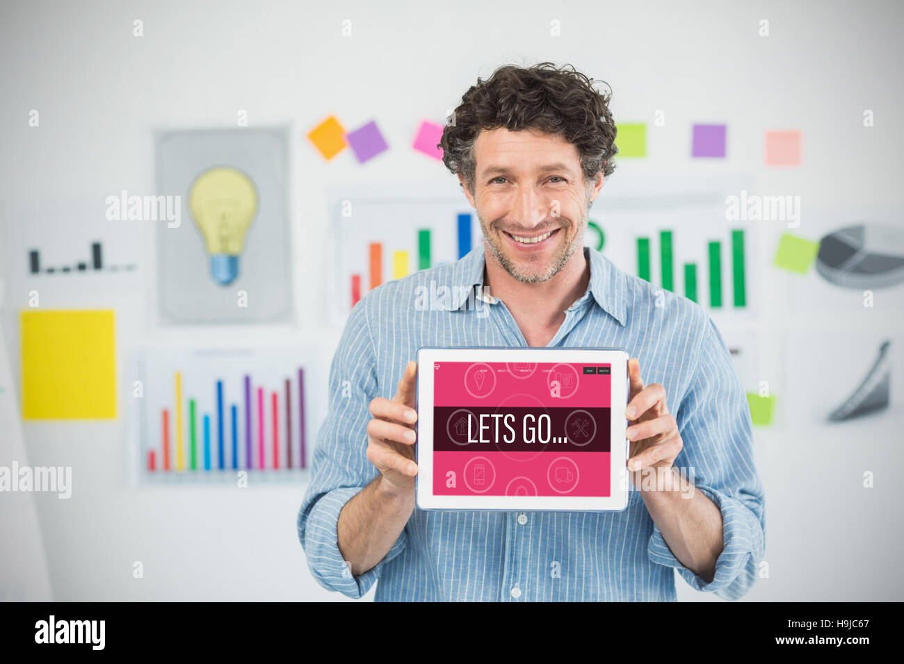 Composite image of businessman showing digital tablet with blank screen in creative office Stock Photo