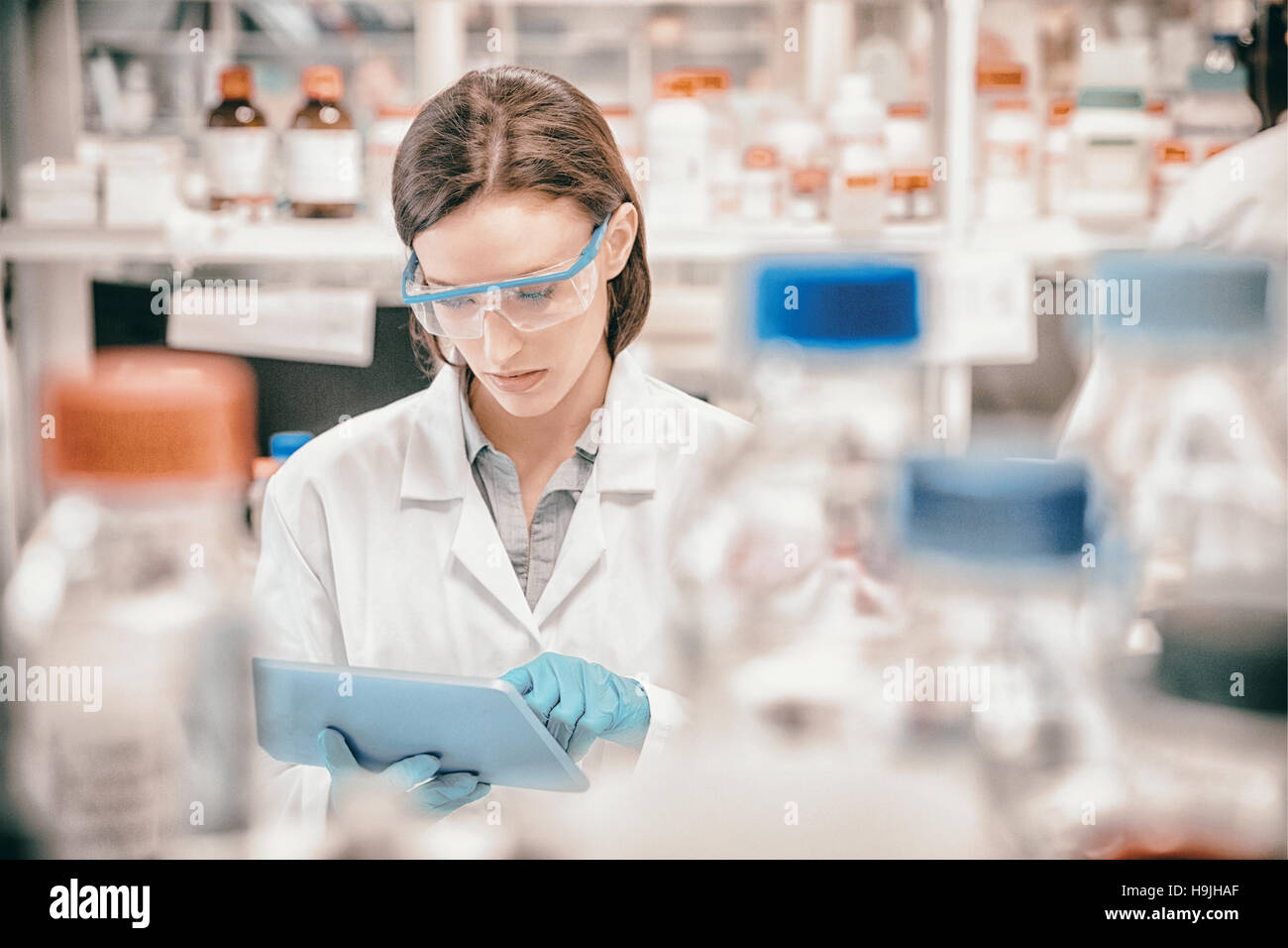 Chemist wearing safety glasses and using tablet pc Stock Photo