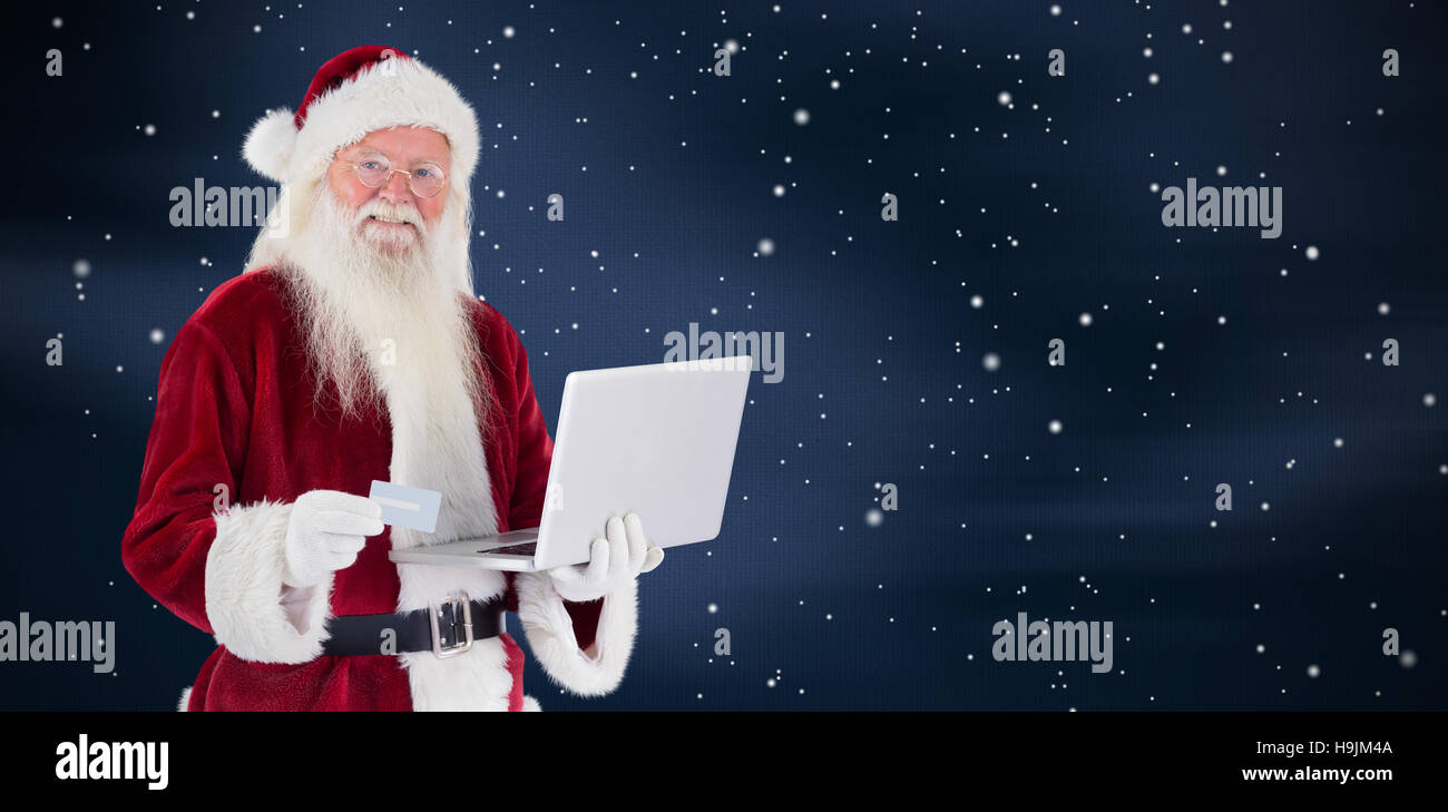 Composite image of santa pays with credit card on a laptop Stock Photo