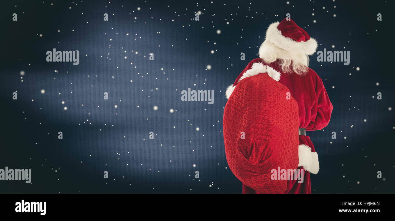 Composite image of santa is holding his bag in one hand Stock Photo