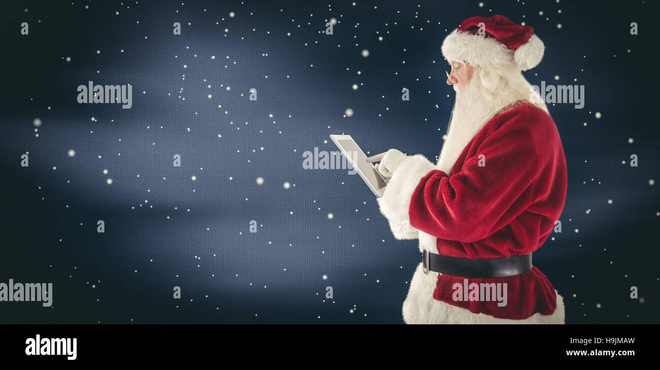 Composite image of santa uses a tablet pc Stock Photo