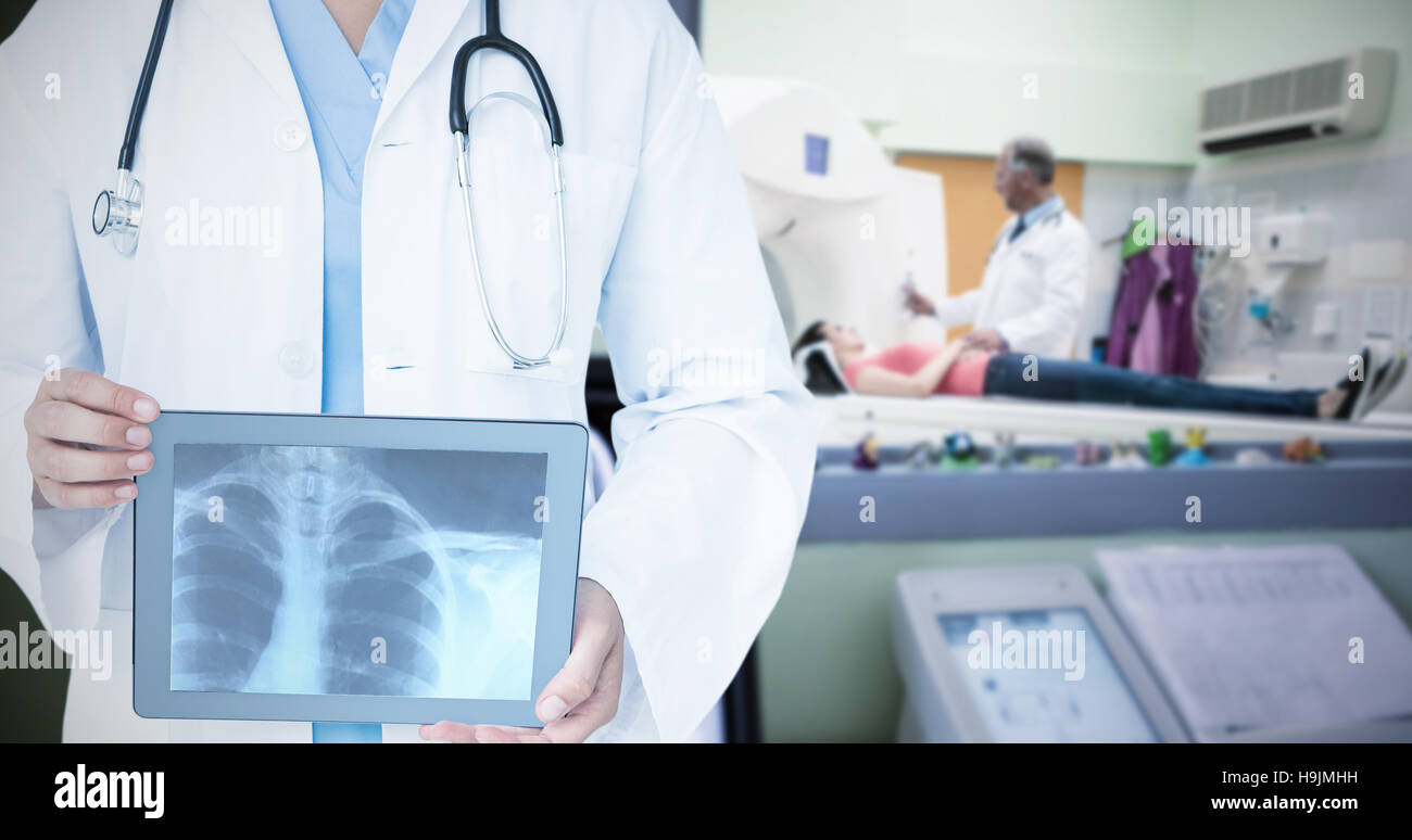 Composite image of doctor looking at xray on tablet Stock Photo