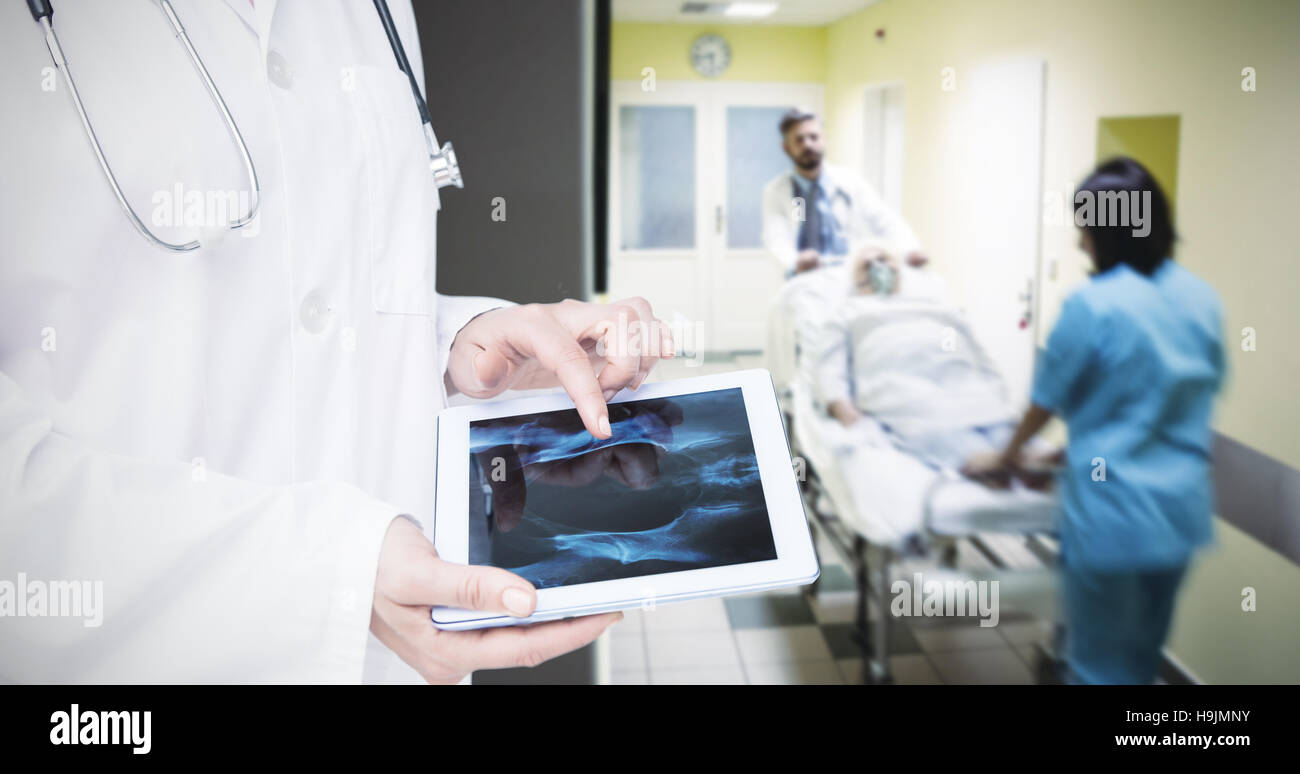 Composite image of doctor looking at xray on tablet Stock Photo