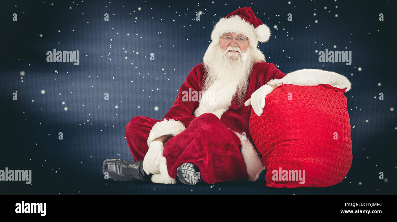 Composite image of santa sits next to his bag Stock Photo