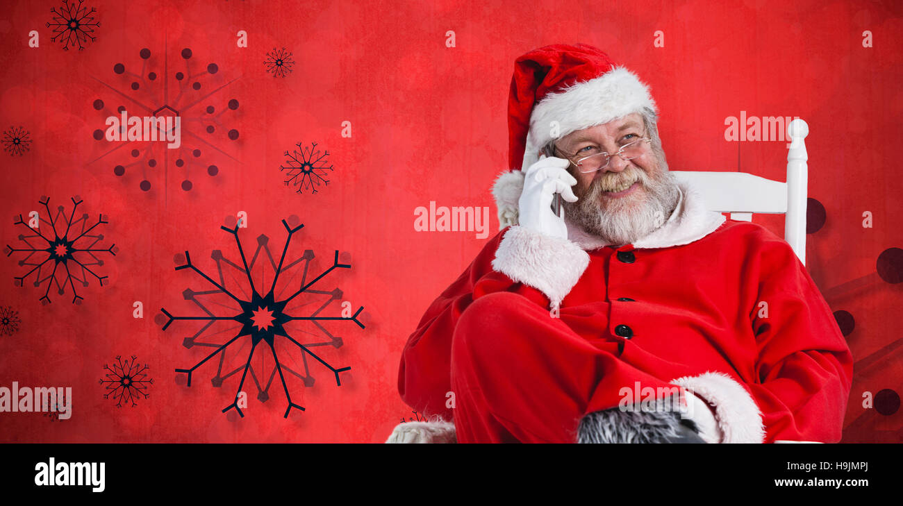 Composite image of santa claus using phone on chair Stock Photo