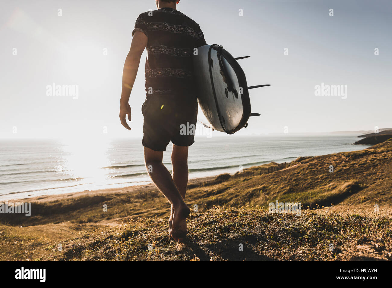 Back view of teenage boy with surfboard walking to the sea Stock Photo