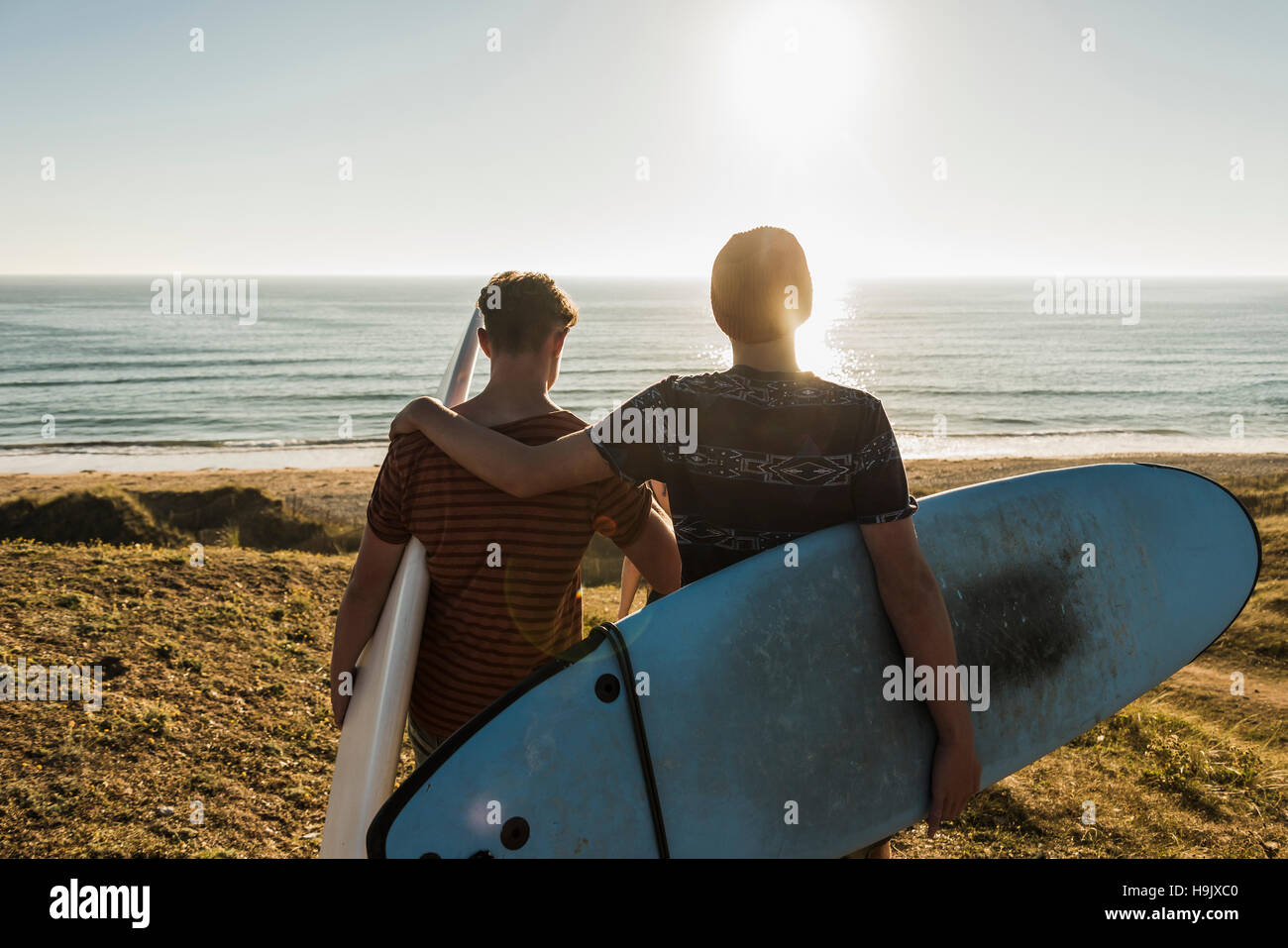 Back view of two best friends with surfboards at seaside Stock Photo