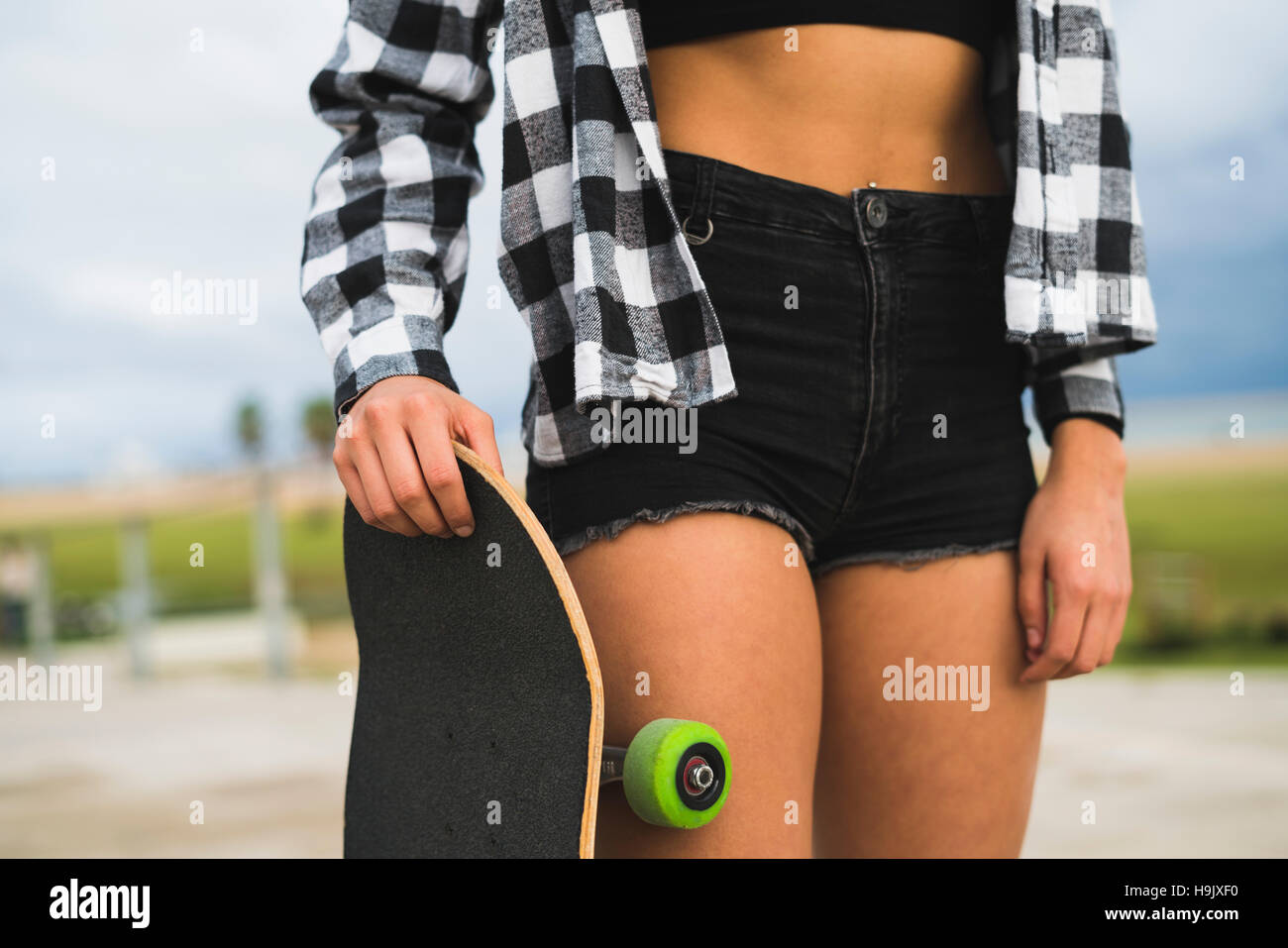 Woman with skateboard wearing black Hot Pants, partial view Stock Photo -  Alamy