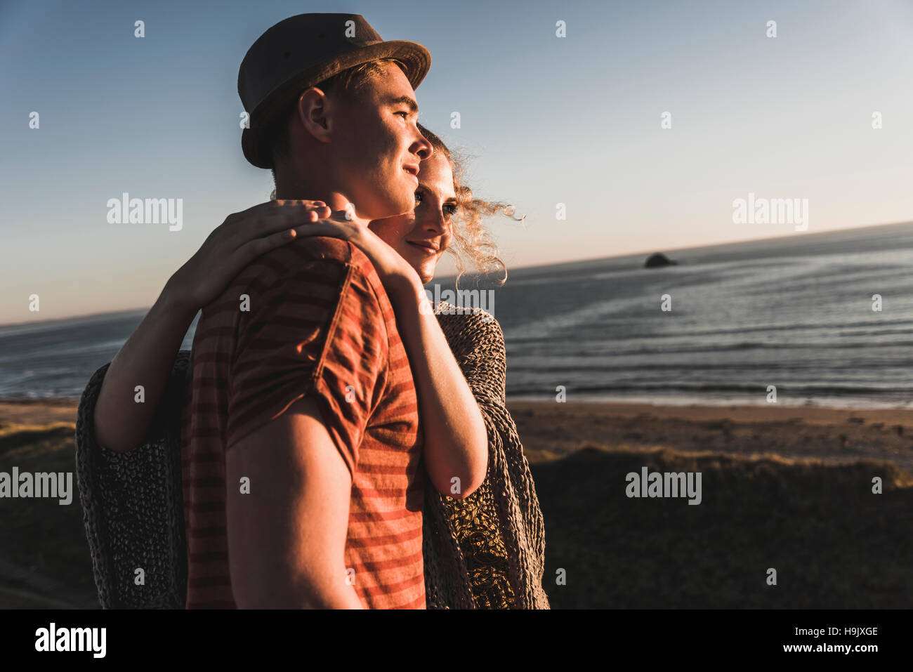 Young couple in love watching sunset on the beach Stock Photo