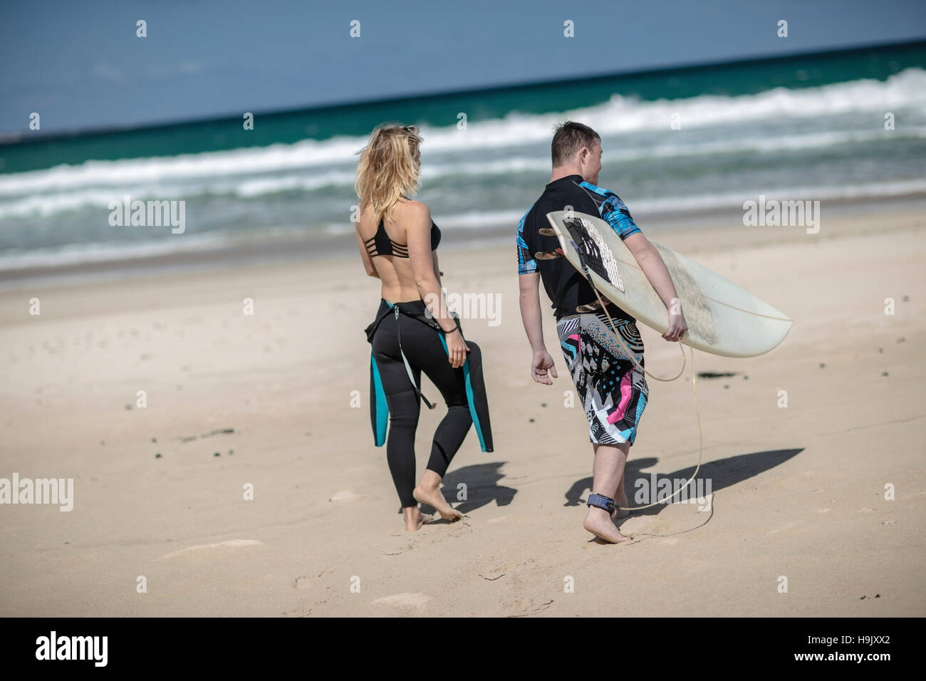 Teenage boy with down syndrome and woman with surfboard on beach Stock Photo