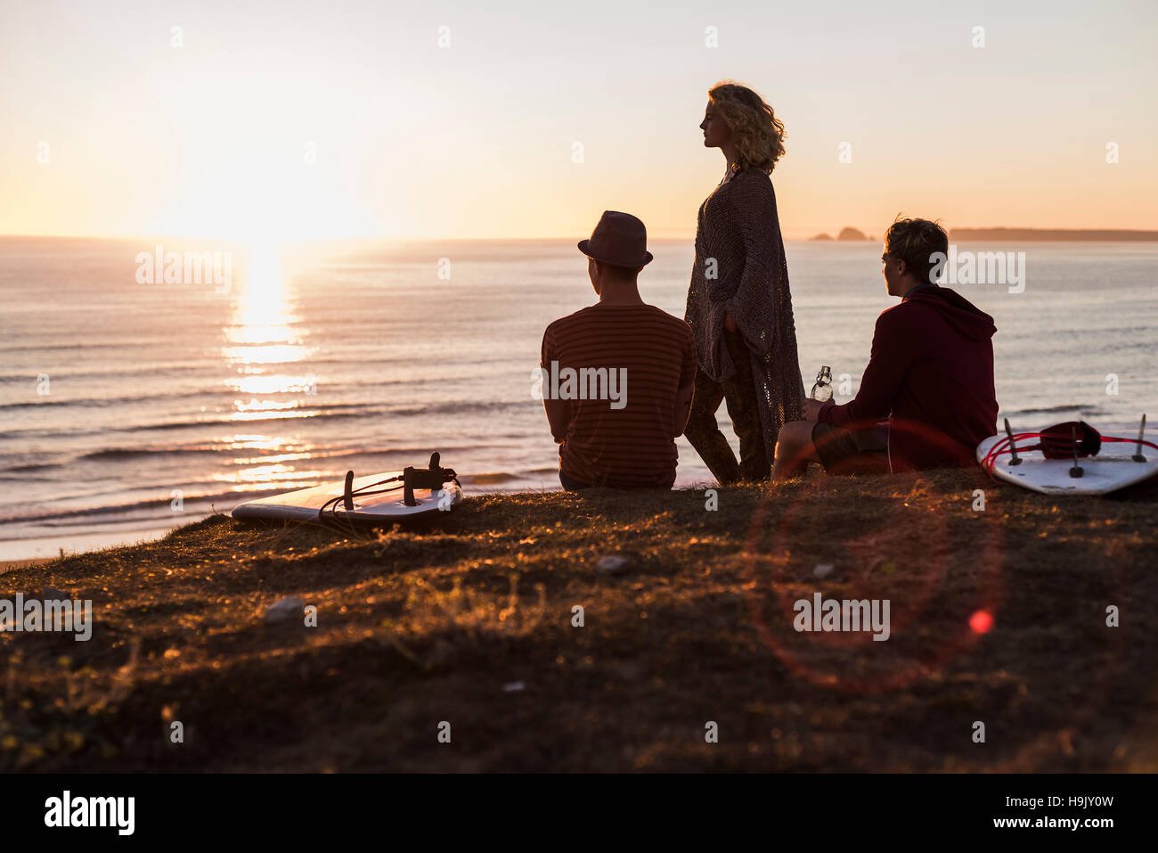 Three friends enjoying sunset on the beach Stock Photo