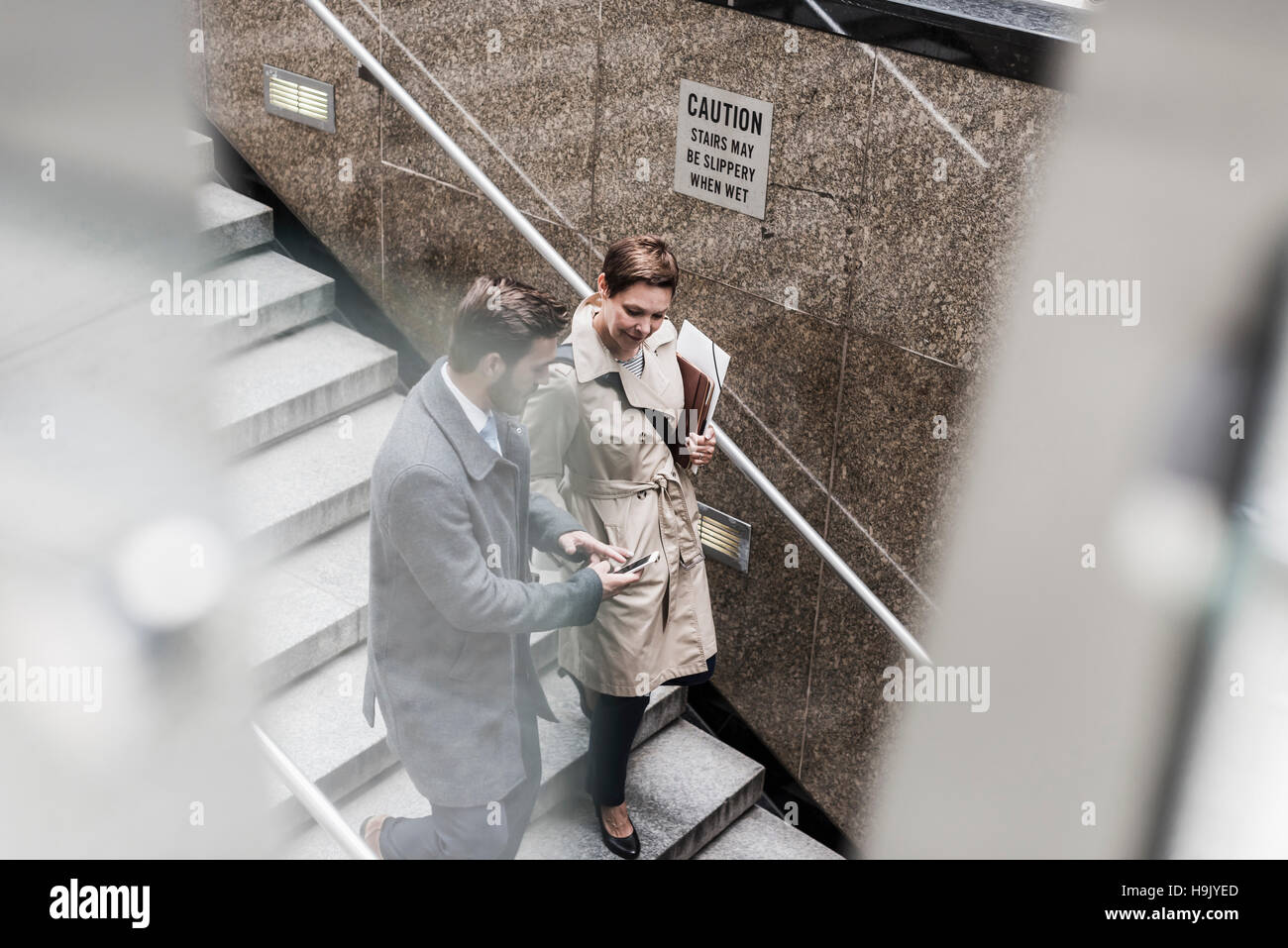 Businessman and woman walking down stairs Stock Photo - Alamy