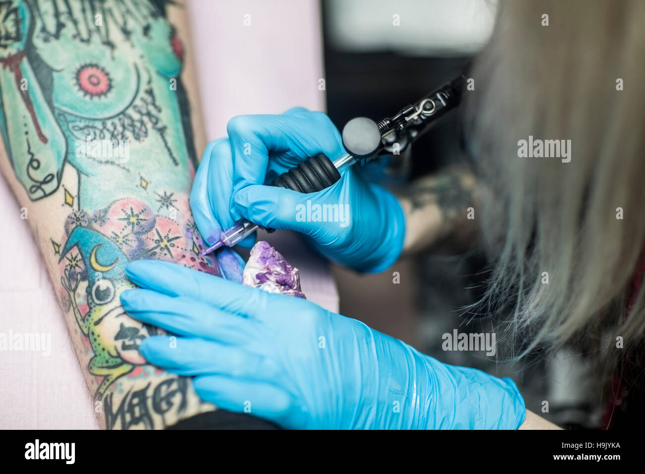 Female Tattoo Artist Tattooing A Leg Stock Photo - Alamy