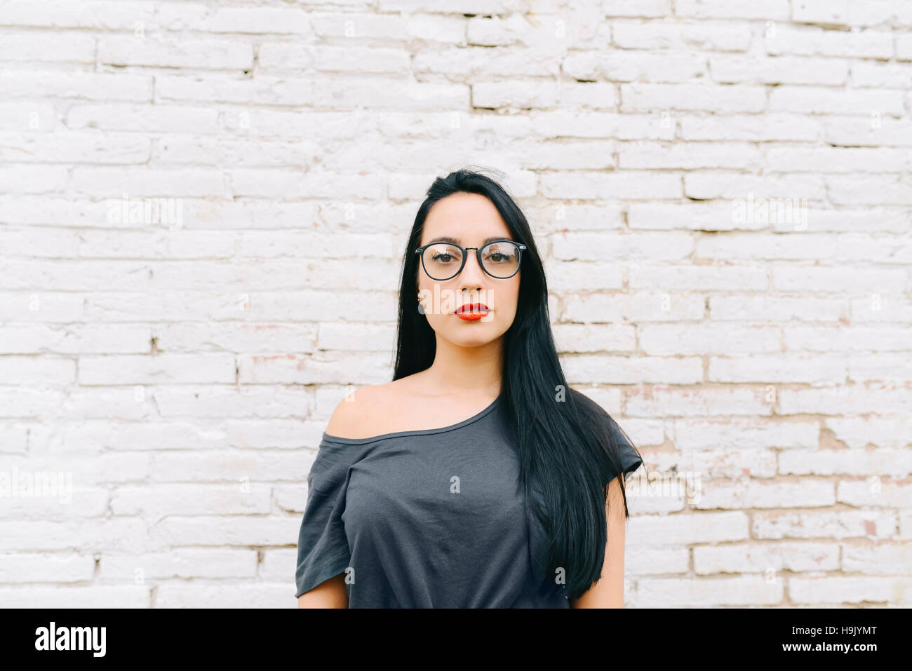 Portrait of young woman in front of brick wall Stock Photo - Alamy