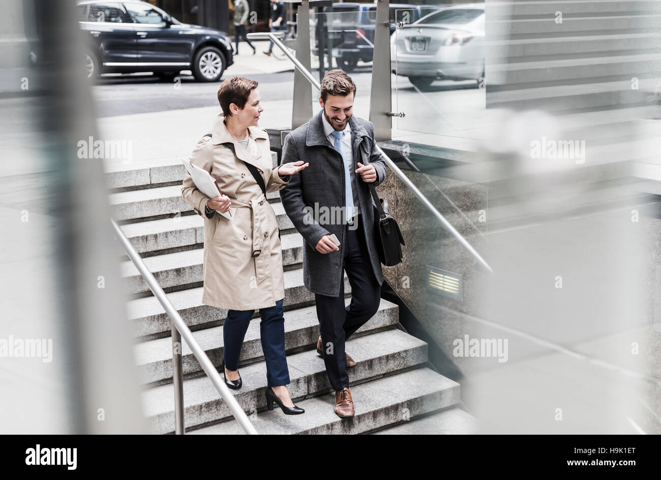 Businessman and woman walking down stairs Stock Photo - Alamy