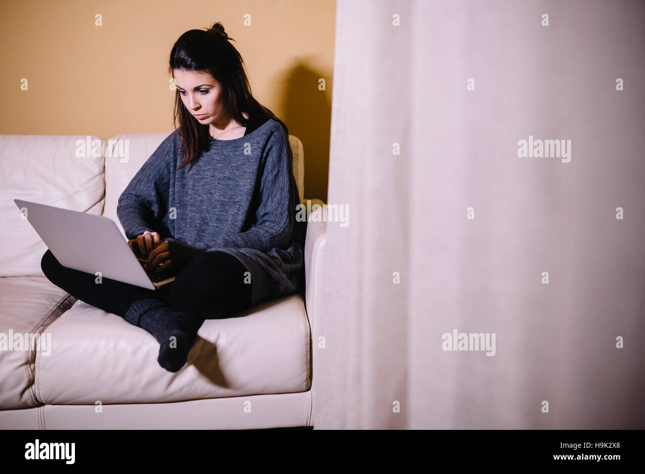 Young woman sitting on the couch using laptop Stock Photo - Alamy