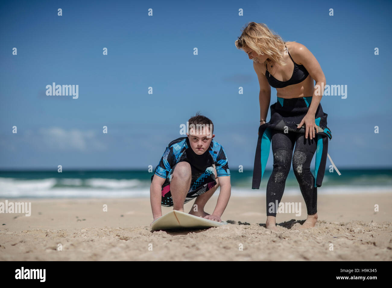 Teenage boy with down syndrome having surf lessons on beach Stock Photo