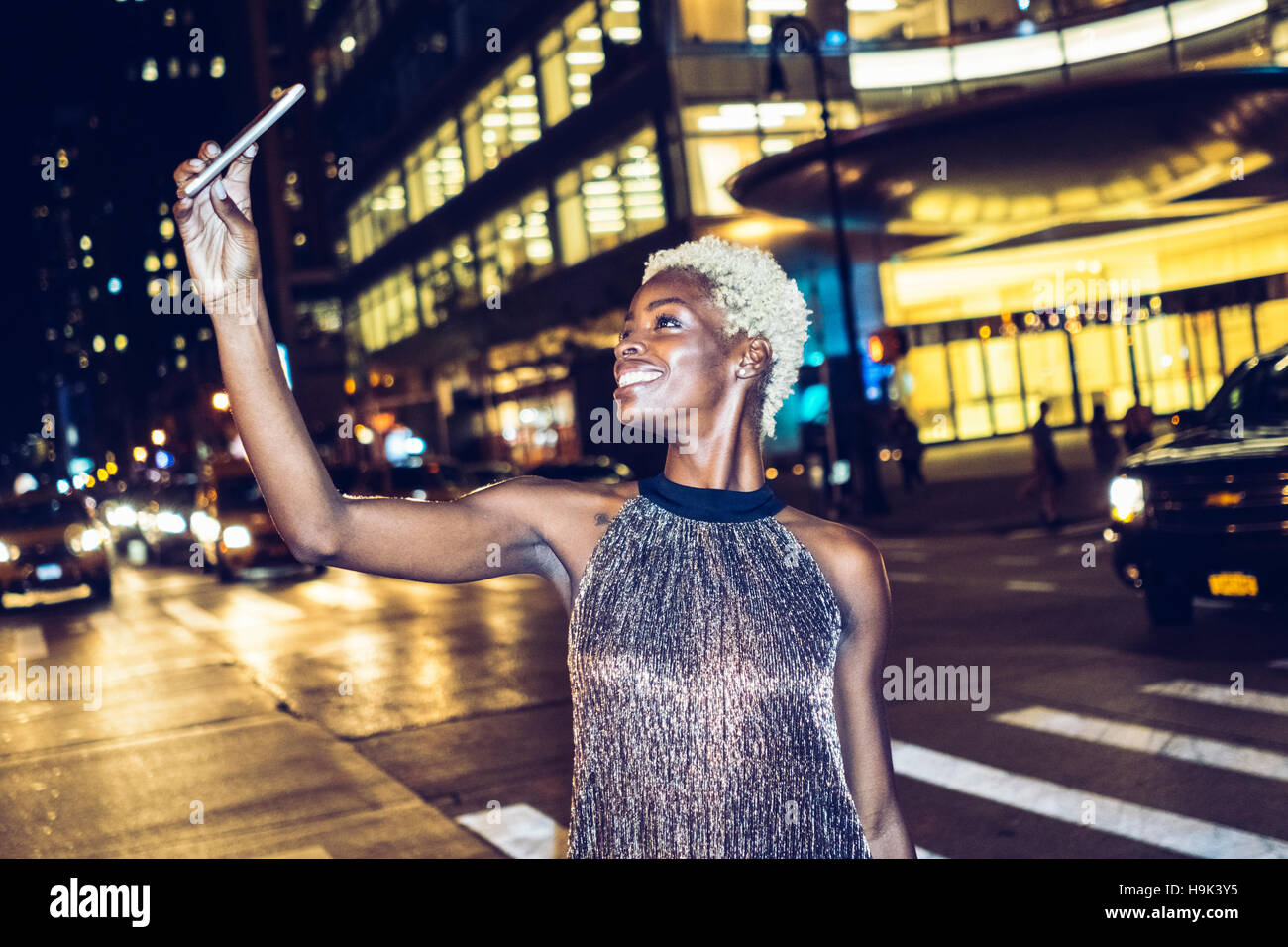 USA, New York City, smiling young woman on Times Square at night taking ...